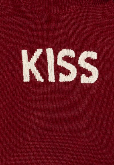 Piros pulóver fehér hímzett "KISS" felirattal. Kötött anyag, kerek nyakú dizájn, sima textúra és közepes vastagság.