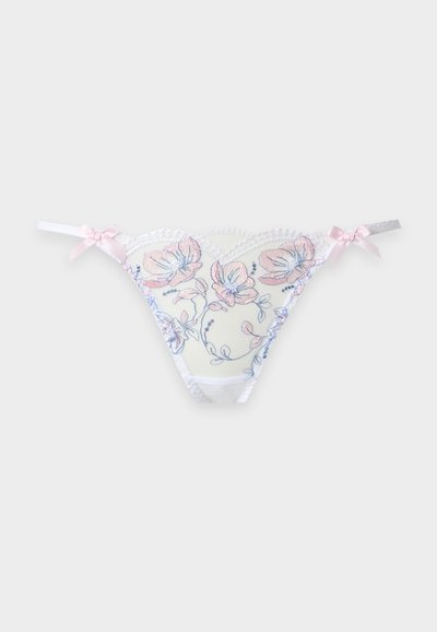 String en dentelle blanche avec broderie florale rose et bleue et petits nœuds roses sur chaque lanière de hanche sur un fond clair.