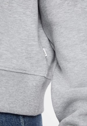 Grey sweatshirt with ribbed cuffs and hem. Features soft texture, subtle fabric pattern, and a small branded label on the side seam.