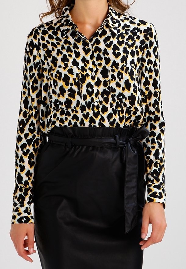 Leopard-print blouse in white, black, and gold, featuring a collar and two chest pockets, paired with a black belted satin skirt.