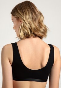 Schwarzer Baumwoll-Bralette mit breiten Trägern, runder Ausschnitt und glattem Bandakzent. Besitzt ein minimalistisches Design und nahtlose Textur.
