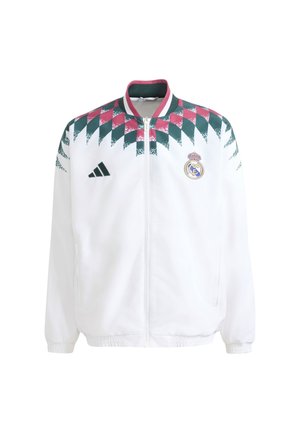 Witte sportjas met rits met rood-groen ruitpatroon op de schouders, Adidas-logo op de linkerborst en Real Madrid-wapen op de rechterborst.
