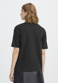 Sort bomuld t-shirt med korte ærmer, rummelig pasform, rund udskæring og minimal syning. Blød tekstur, ingen synlige mønstre eller hardware.