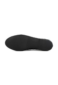 Zwarte rubberen schoenzool met een gestructureerd oppervlak, voorzien van ribbels en een glad gedeelte, ontworpen voor grip en duurzaamheid.