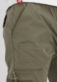 Olivgrüne Cargo-Hosen mit mehreren Taschen, elastischem Bund und verstellbarem Kordelzug. Hergestellt aus leichtem, glattem Material.
