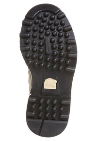 Semelle extérieure en caoutchouc noir avec des motifs de traction circulaires et un patch logo Sorel. La semelle présente une finition texturée pour une meilleure adhérence et durabilité.