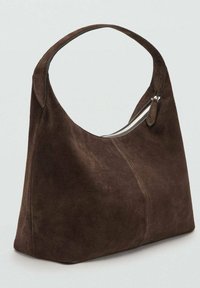 Brązowa torba zamszowa o zaokrąglonym kształcie, z pojedynczym zakrzywionym uchwytem i srebrnym zamkiem błyskawicznym po boku. Miękka faktura i minimalistyczny design.