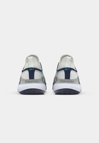 Adidași Reebok cu un upper din plasă gri, accente bleumarin și o talpă albă. Caracteristici notabile includ un tab pentru tragere și un panou posterior texturat.