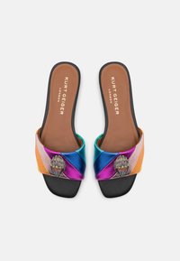 Chanclas de múltiples colores con una correa metálica texturizada que presenta un acento decorativo en forma de mano. Suela negra y plantilla marrón.