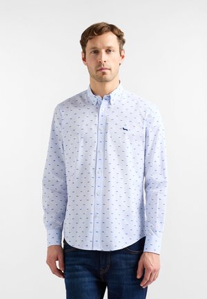 Lyseblå skjorte med knapper og mønster af små hunde i mørkere blå, med standardkrave og lange ærmer.