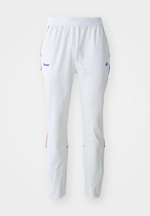 Hvite treningsbukser med elastisk midjebånd, med røde og blå detaljer på sidesømmer og en logo på venstre hofte.