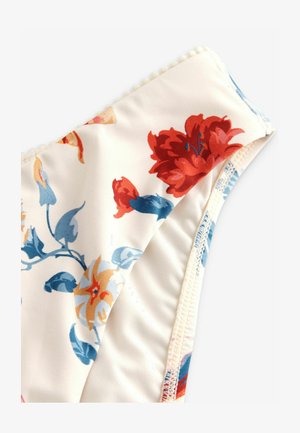 Kvetinový bikiny vrch v krémovej farbe s červenými a modrými kvetmi. Hladká tkanina s picot lemovaním pozdĺž okrajov. Zakrivený tvar, jemná textura.