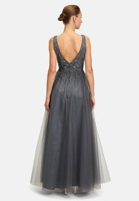 Graues Abendkleid mit tiefem V-Ausschnitt im Rücken, verziertem Oberteil und fließendem Tüllrock. Beinhaltet filigrane Perlenarbeit und eine taillierte Taille.