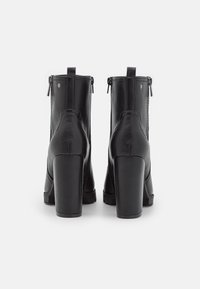Czarne botki za kostkę z gładkiej skóry, z masywnym słupkowym obcasem, tylnym zamkiem błyskawicznym oraz okrągłym kształtem.