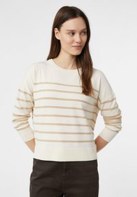 Beżowy sweter w paski wykonany z miękkiej dzianiny. Długie rękawy z ściągaczami na mankietach i u dołu. Neutralna paleta kolorów z poziomymi paskami.