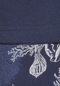 Marineblaue Stoff mit weißen botanischen Motiven von Korallen und Meereslebewesen; glatte Textur mit kontrastierendem Stich an der Naht.
