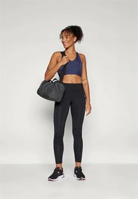 Leggings neri abbinati a un reggiseno sportivo blu navy, completati da una borsa da ginnastica grigia e scarpe da ginnastica nere con dettagli rosa. Abbigliamento leggero e sportivo.