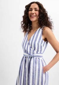 Gestreiftes Leinenkleid in Blau und Weiß mit V-Ausschnitt, ärmellosem Design, Taillenschnürung und seitlichen Taschen. Glatte Textur und lässige Passform.