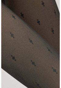 Medias marrones transparentes con una textura acanalada, que presentan un sutil patrón de pequeños diamantes y círculos negros repartidos por toda la tela.