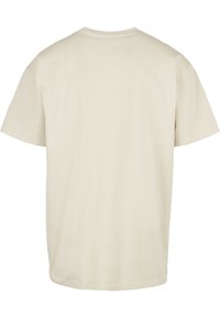 Beige bomull t-skjorte med rund hals og korte ermer, med en enkel design og glatt tekstur. Bakvinkel vises.