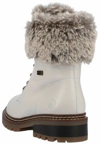 Botte en cuir blanc avec un revers en fausse fourrure, bout rond et semelle en caoutchouc marron. Comprend des œillets métalliques et des détails de couture marron.