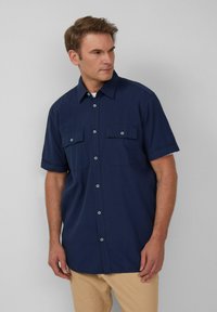 Korte mouw button-up shirt van navy stof met een gestructureerde afwerking, voorzien van twee borstzakken en contrasterende lichtblauwe knopen.
