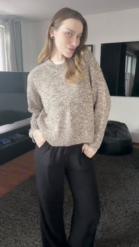 Lysebrun strikket sweater med en tekstureret finish, kombineret med loose sort bukser. Outfit'et har en afslappet pasform og et casual look.