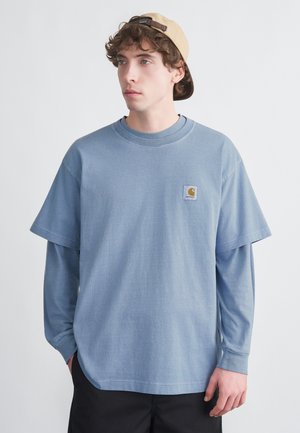 Light blue, short-sleeve T-shirt with an oversized fit, featuring a round neckline and a small logo patch on the chest.