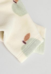 Fleece-tyg, krämfärgad bas med abstrakta mönster i grönt, brunt och lila. Mjuk textur med rundade former och subtila sömnadsdetaljer.