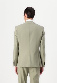 Chaqueta de traje verde claro con solapa muesca, dos botones, una abertura trasera y puños abotonados. Tejido suave con corte ajustado.