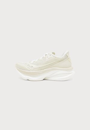 Chaussure de sport beige clair avec une semelle blanche épaisse et sculptée et une tige en mesh, vue de côté sur un fond uni.