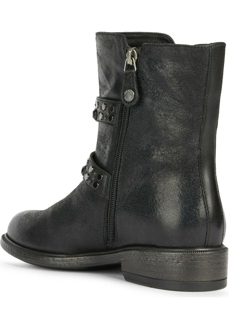 Bottine noire en cuir texturé. Dotée de deux sangles décoratives avec des clous en argent et d'une fermeture éclair sur le côté. Talon bas empilé.