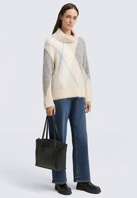 Maglione a maglia grossa color crema con motivo a diamanti grigi e azzurri. Abbinato a jeans scuri e borsa a tracolla nera. Tessuto liscio, vestibilità oversize.