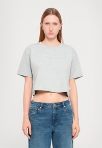 Gray cropped t-shirt with short sleeves, featuring an embossed logo. Paired with light blue high-waisted denim jeans. Smooth fabric texture.