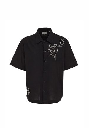 Fekete, rövid ujjú gombos ing, fehér hímzett virágmintákkal a jobb felső mellrészen és az alsó bal oldalon.
