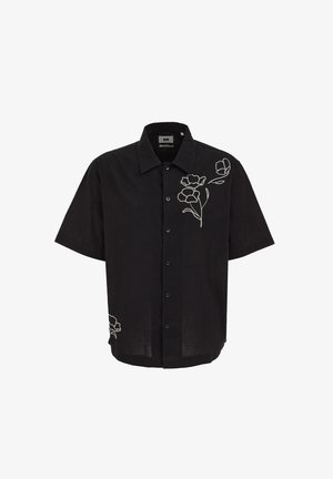 Fekete, rövid ujjú gombos ing, fehér hímzett virágmintákkal a jobb felső mellrészen és az alsó bal oldalon.