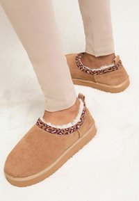 Brūnganas zābaku tipa čības ar mākslīgās kažokādas oderi, leoparda raksta akcentiem apkārt apkaklei un teksturētu gumijas zolīti.