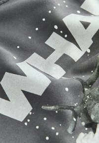 Szary materiał z dużym białym tekstem i graficznym wzorem. Tekstura wydaje się gładka z lekkim połyskiem, uzupełniona detalami w postaci rozprysku.