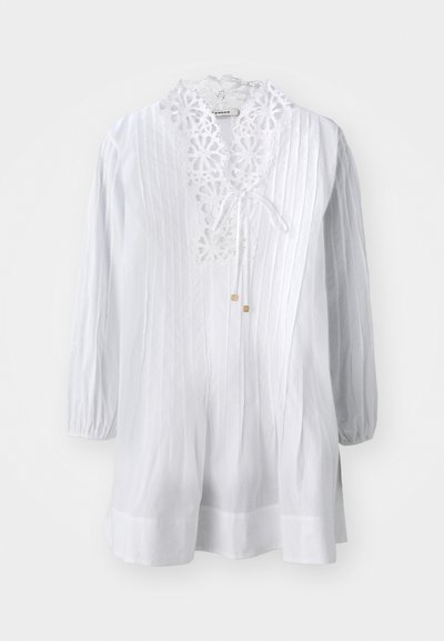 Blusa bianca con colletto in pizzo decorativo, maniche lunghe a sbuffo e righe verticali. Include una chiusura a cravatta e sottili dettagli dorati.