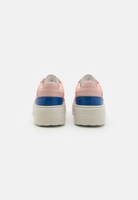 Baskets rose pâle et bleues avec une semelle blanche épaisse et une texture douce ; présente des détails de couture et un logo à l'arrière.