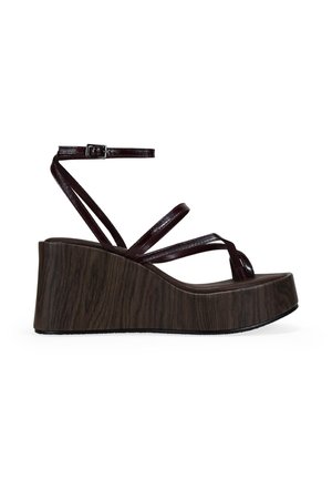 Sandalia de cuña con suela de plataforma con textura de madera oscura y finas tiras brillantes de color marrón oscuro, con cierre de hebilla en el tobillo.