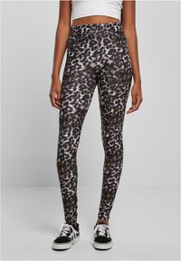 Hög midja leggings i svart och grå leopardmönster, med ett sträckbart tyg och en figursydd design. Accenterade med vita sneakers.