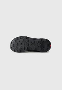 Black rubber shoe sole with a textured grip pattern featuring hexagonal and circular shapes, designed for traction and durability.