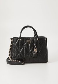 Black quilted handbag with top handles, gold chain strap, embossed logo pattern, and triangular metal Guess logo on front.