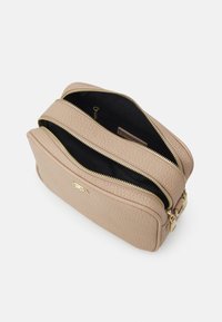 Borsa a tracolla in pelle beige con due scomparti con zip, superficie texturizzata e accessori in tonalità oro. L'interno è in tessuto nero.