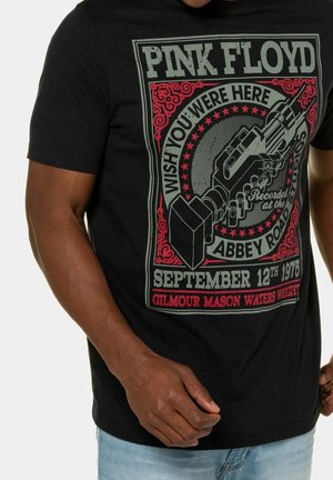 Schwarzes Pink Floyd T-Shirt mit Text über Abbey Road Studios und den 12. September 1975, mit einer Grafik einer Hand, die einen Tonbandgerät hält.