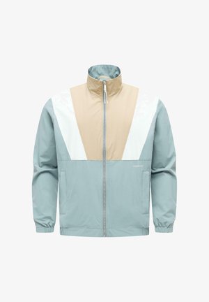 Giacca antivento azzurro chiaro con pannelli color blocco beige e bianco, zip frontale, colletto alto, polsini elastici e tasche laterali.