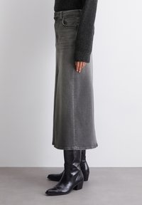 Gray denim skirt with a flared design, knee-length, featuring visible stitching. Paired with black leather ankle boots.