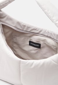 Borsa a spalla imbottita beige con superficie morbida e testurizzata. Presenta una tasca interna con un'etichetta nera che legge "even&odd." Chiusura con cerniera.