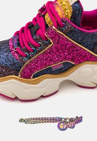 Sneaker multicolore glitterato con accenti rosa, rifiniture dorate e una suola bianca spessa. Include una catena decorativa con un charm a forma di logo.